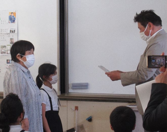 北茂安小学校の代表児童に岡町長が古賀稔彦物語を贈呈している写真